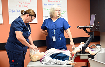 Two nurses practice bagging a mannequin using a Resuscitation Quality Improvement program.