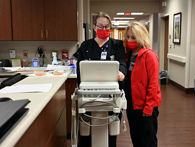 Picture of two female Physicians looking down at a Machine at the Nurses Station