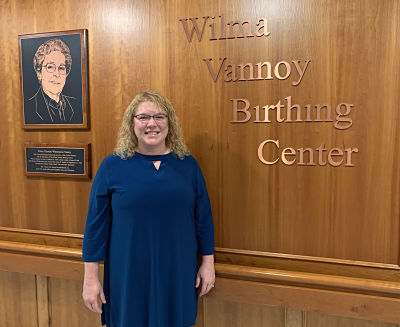 Picture of Dr. Melinda Wonsick dressed nicely while standing in front of The Wilma Vannoy Birthing Center smiling