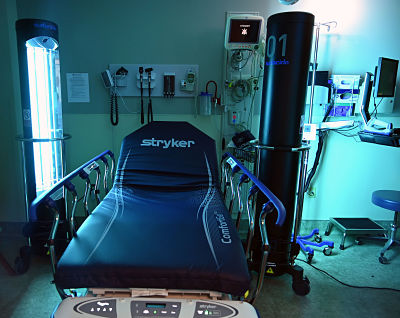The Surfacide Helios&#xAE; UV-C Disinfection System uses UV-C light energy to eliminate deadly pathogens on hard surfaces.Picture of a hospital stretcher in a hospital room with a Suracide Helious UV-C Disinfection System next to it