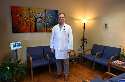 Picture of Dr. Charles Jones, Surgeon- standing in a waiting room. He is smiling.