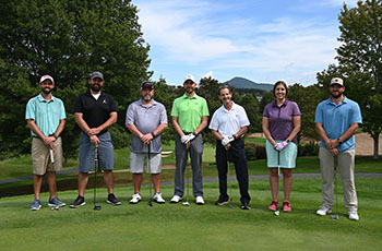 A group of golfers stand together with their clubs on the putting green before the start of the AMH Foundation&apos;s annual Frank M. James Golf Tournament.
