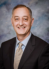 Headshot of male physician in suit jacket and tie.