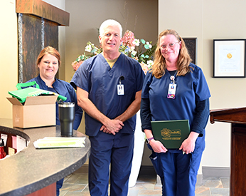 Chris-Anna Donachy, RN, right, was named this year's DAISY Award winner.Photo of two female nurses and a male nurse smiling with an award.