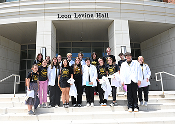 Group of high school medical camp students standing on steps in front of a college building.