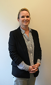Photo of female nurse practitioner standing in front of a wall.
